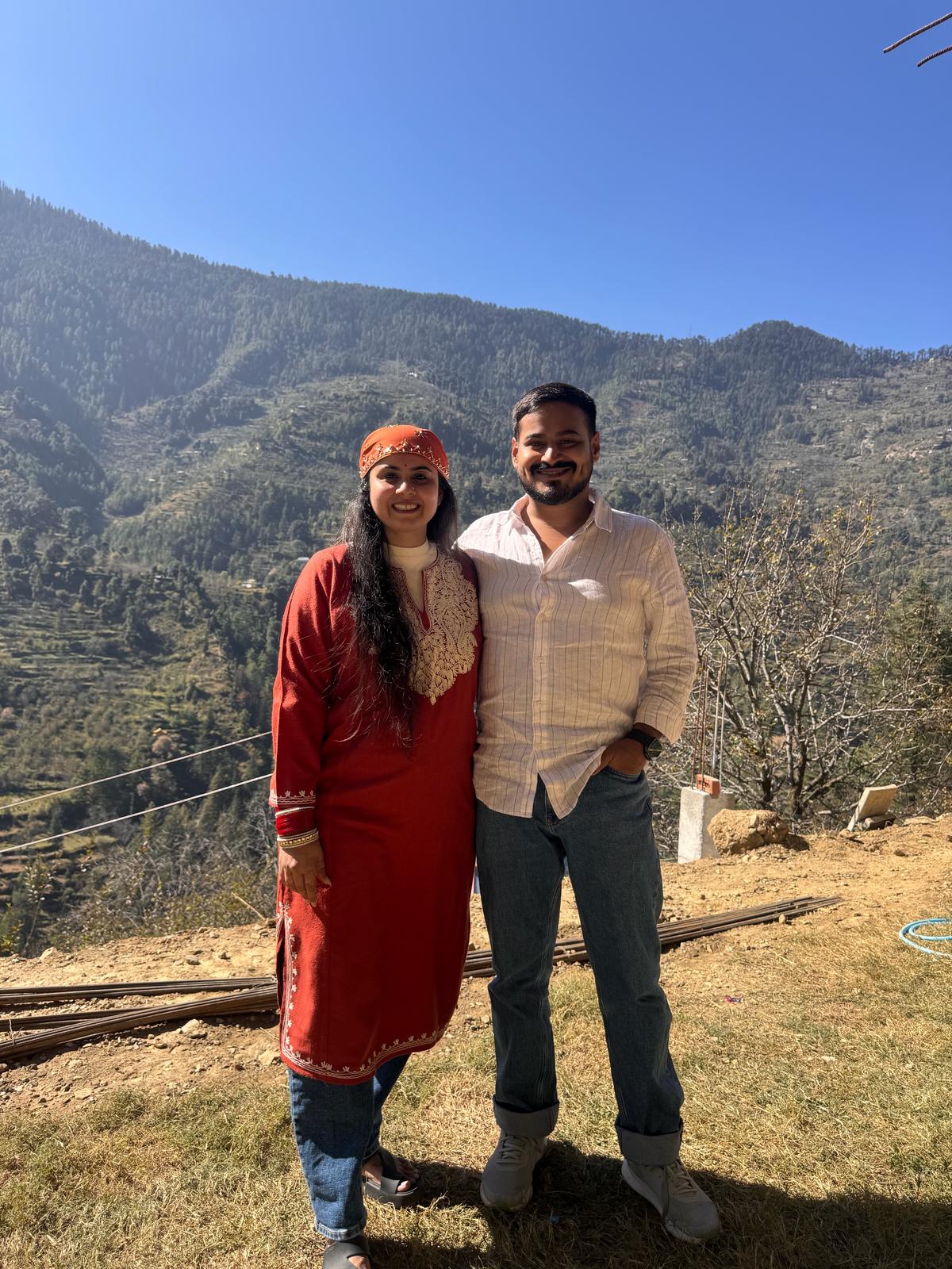 A couple with the valley behind, she in a Himachali dress